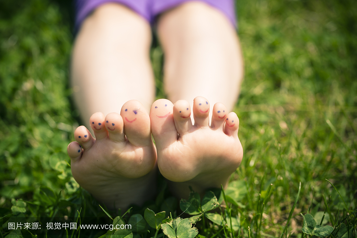 小女孩的脚与脚趾躺在草地上