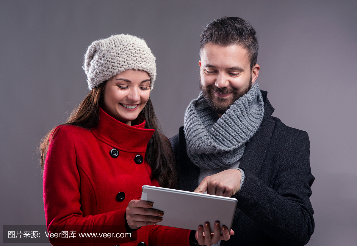 年轻的女人和男人在冬天大衣与平板电脑