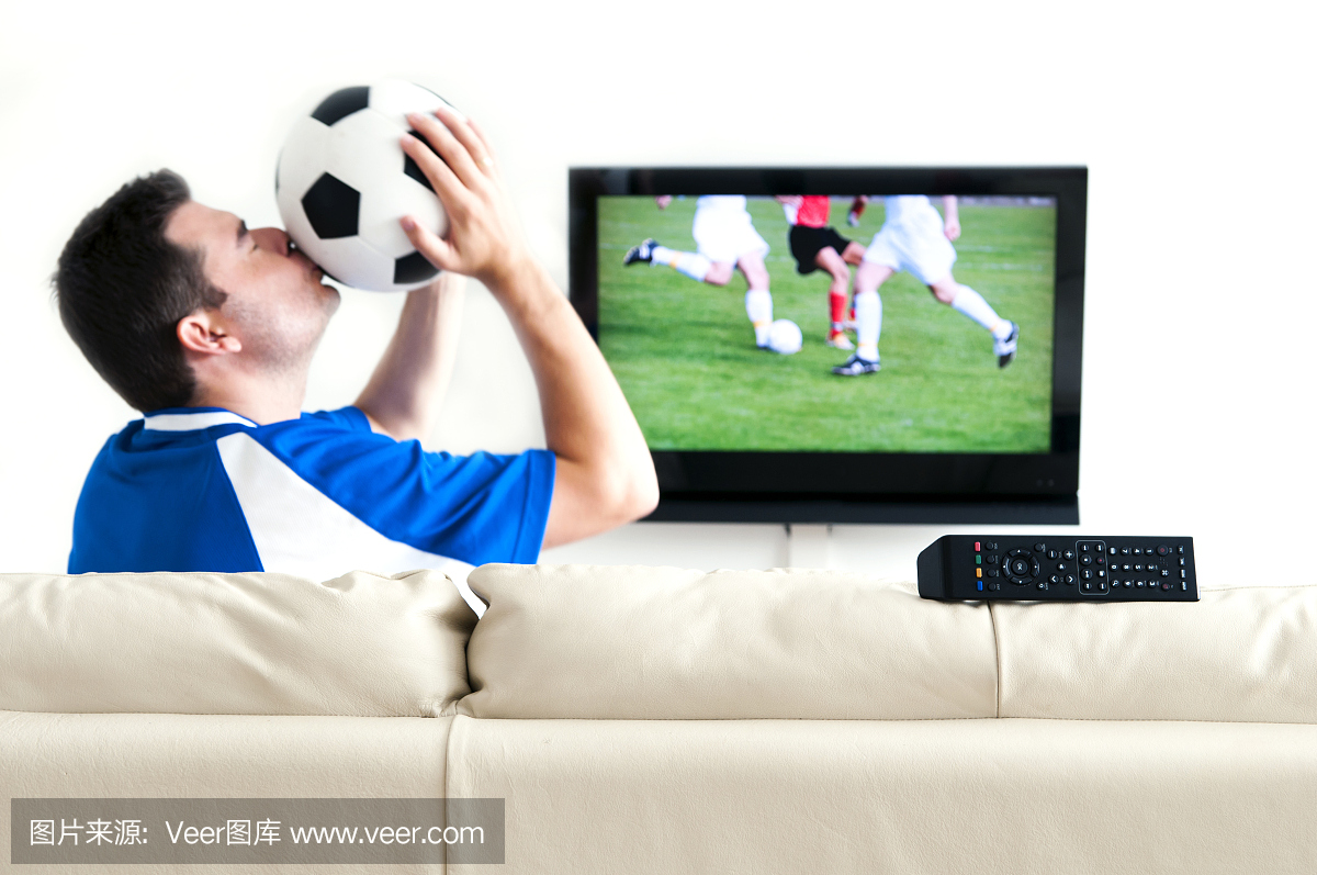 一个男人在电视上看足球时亲吻他的足球