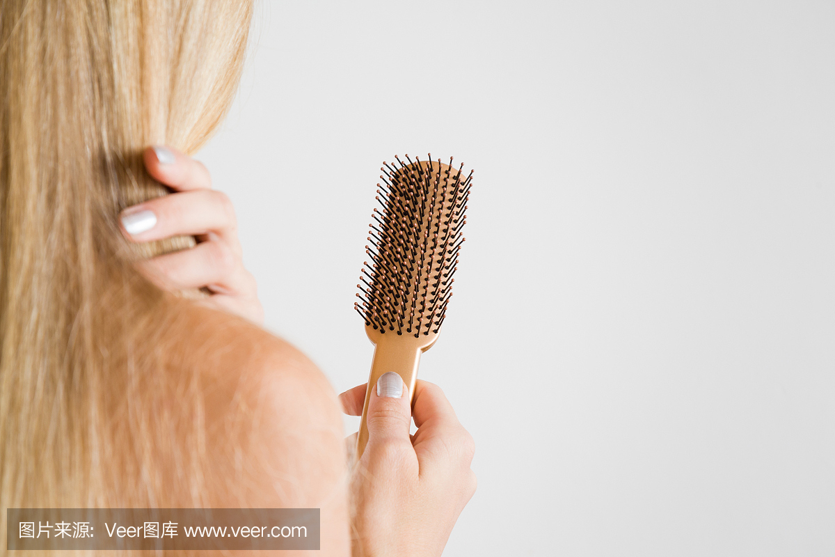 女人触摸的头发,看着梳子。关心健康和干净的