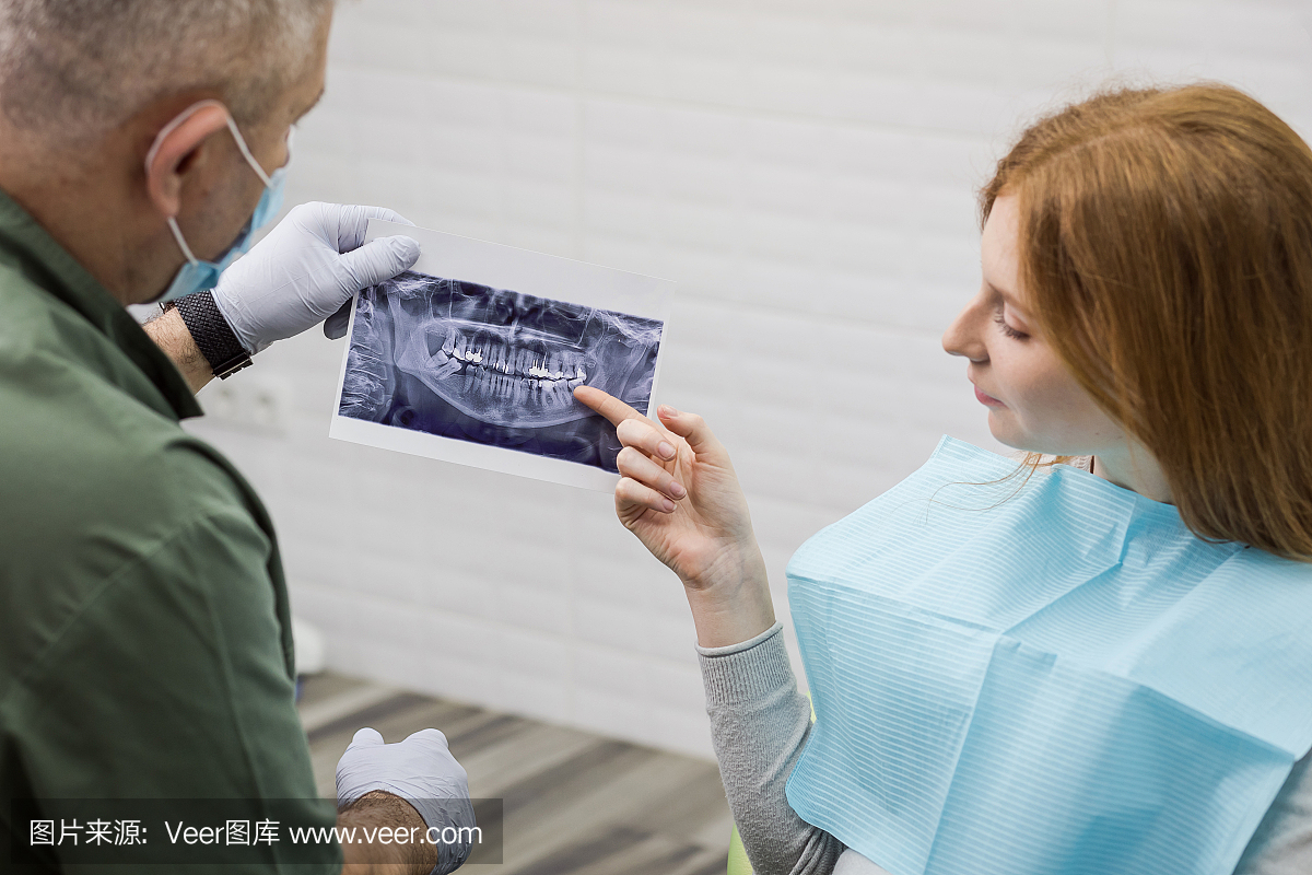 牙医在诊所向他的病人解释X射线牙齿图片的细