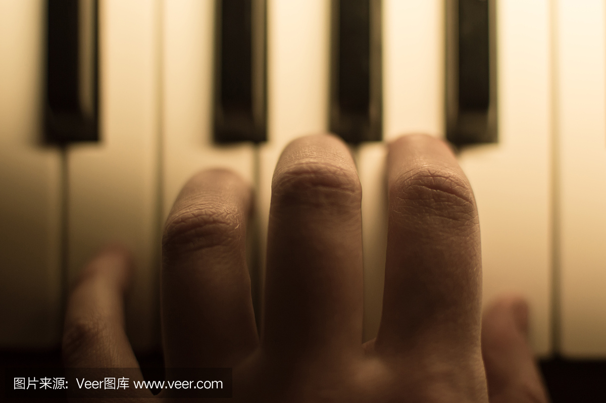 手指弹奏钢琴的特写调色大气照片。键。概念: