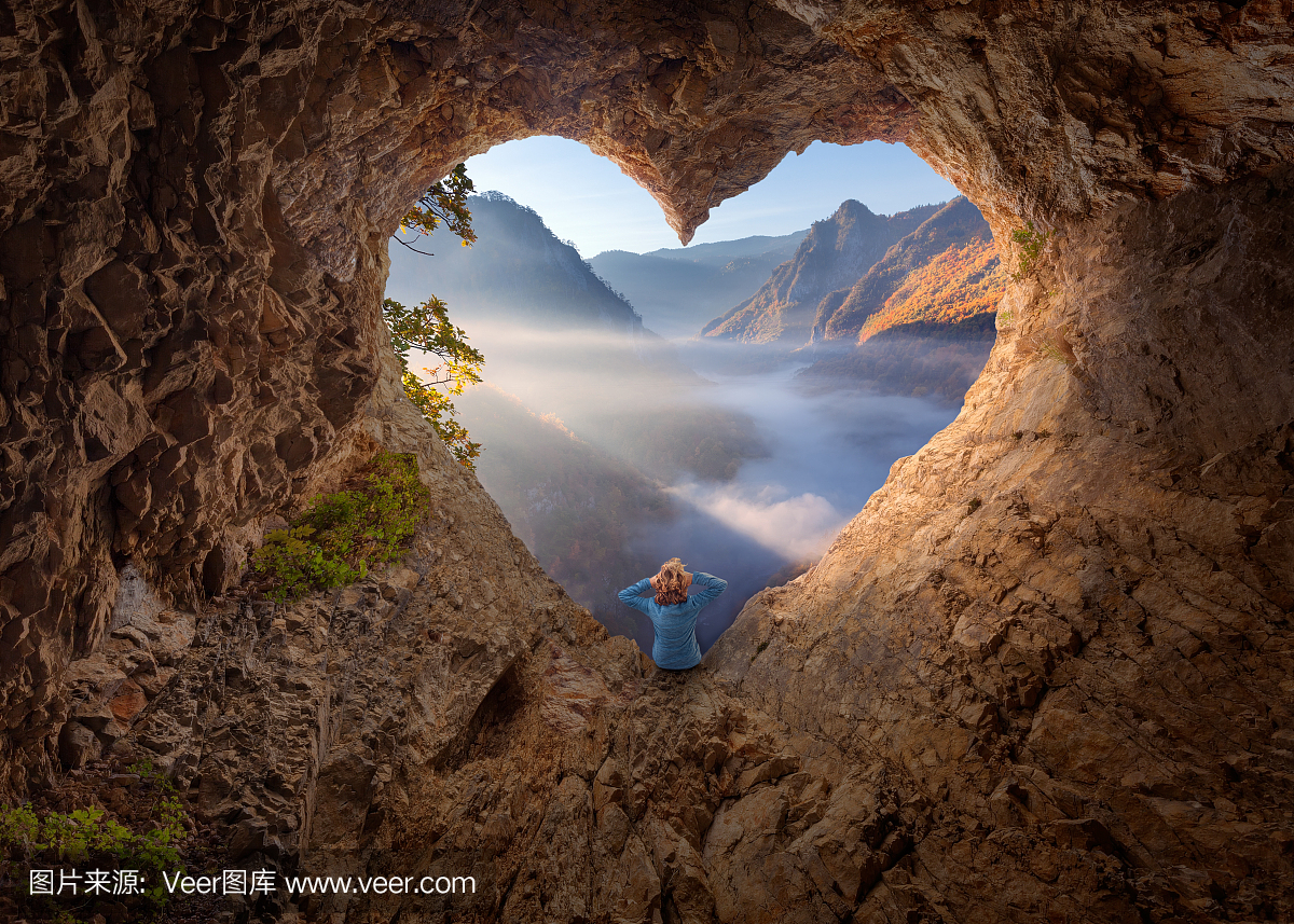 心形洞穴在早上看着迷雾峡谷的女人