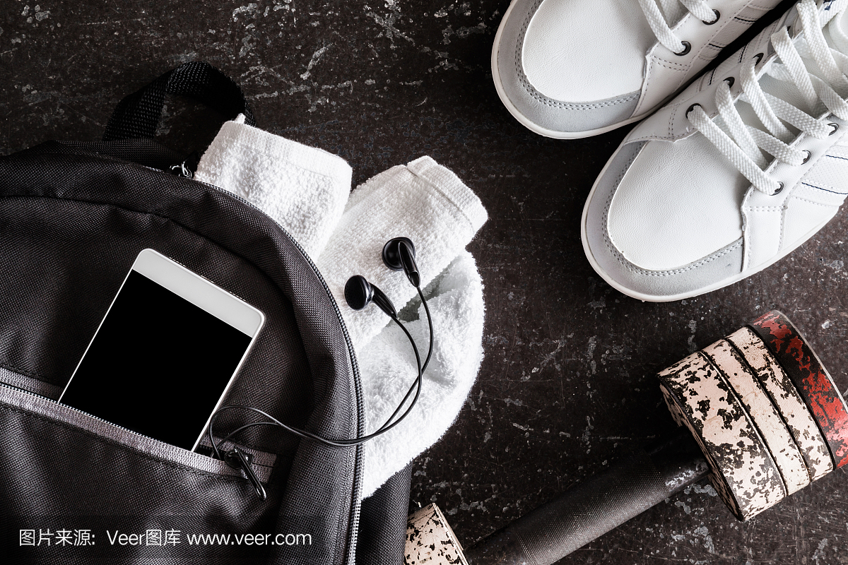 在健身房的黑暗地板上的健身配件。运动鞋,哑