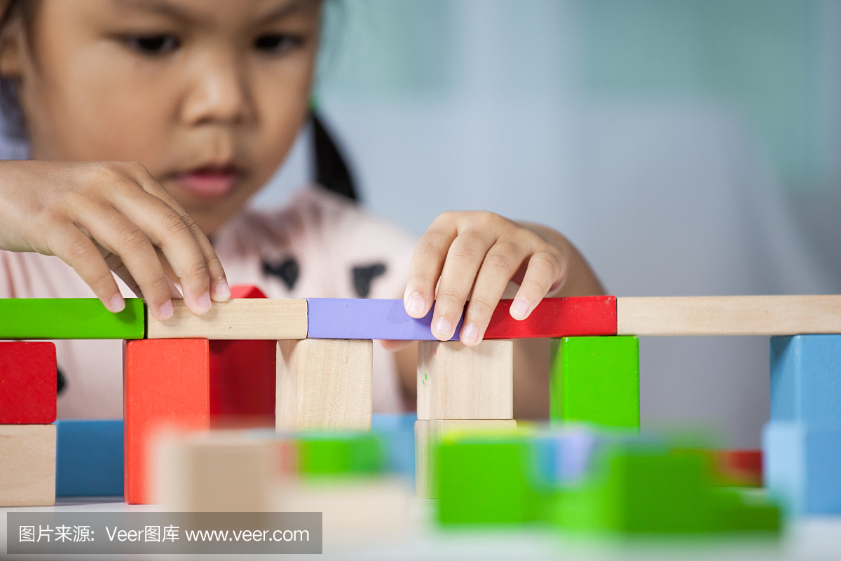 专注于可爱的小女孩,在房间里玩多彩木制积木