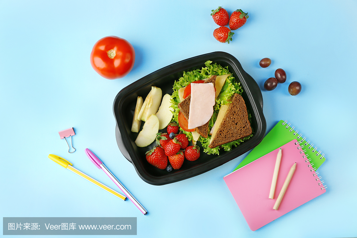 Lunchbox with tasty dinner and stationery on blu