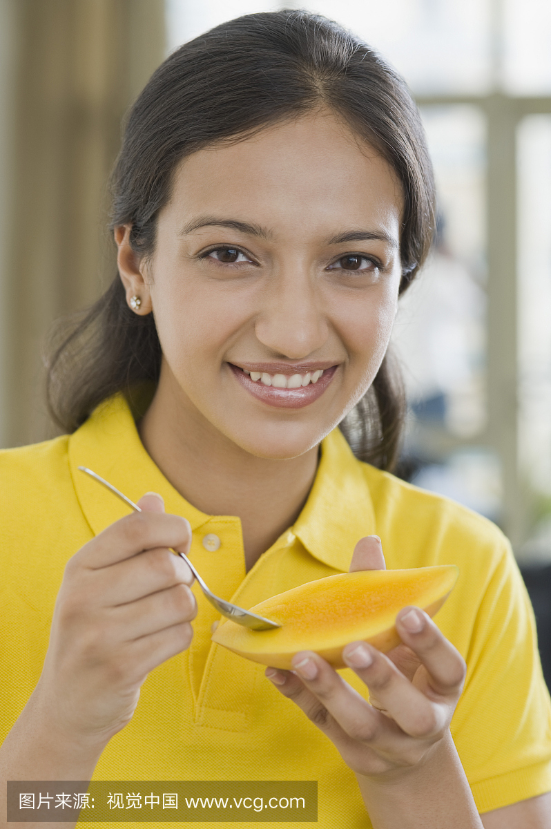 用勺子吃芒果的女人