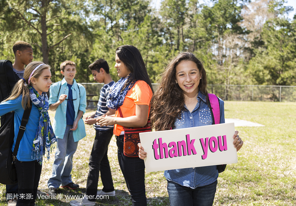 青少年拉丁女孩抱着谢谢登录公园。