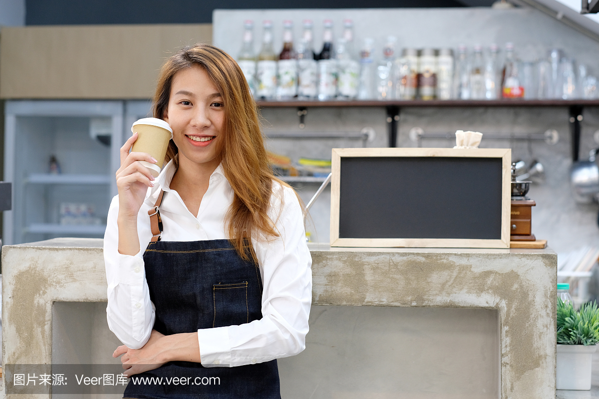 年轻的亚洲女人咖啡师拿着一次性咖啡杯,带着
