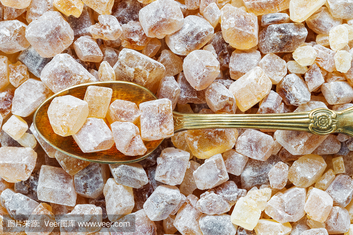 焦糖红糖在汤匙。甘蔗糖立方体背景。