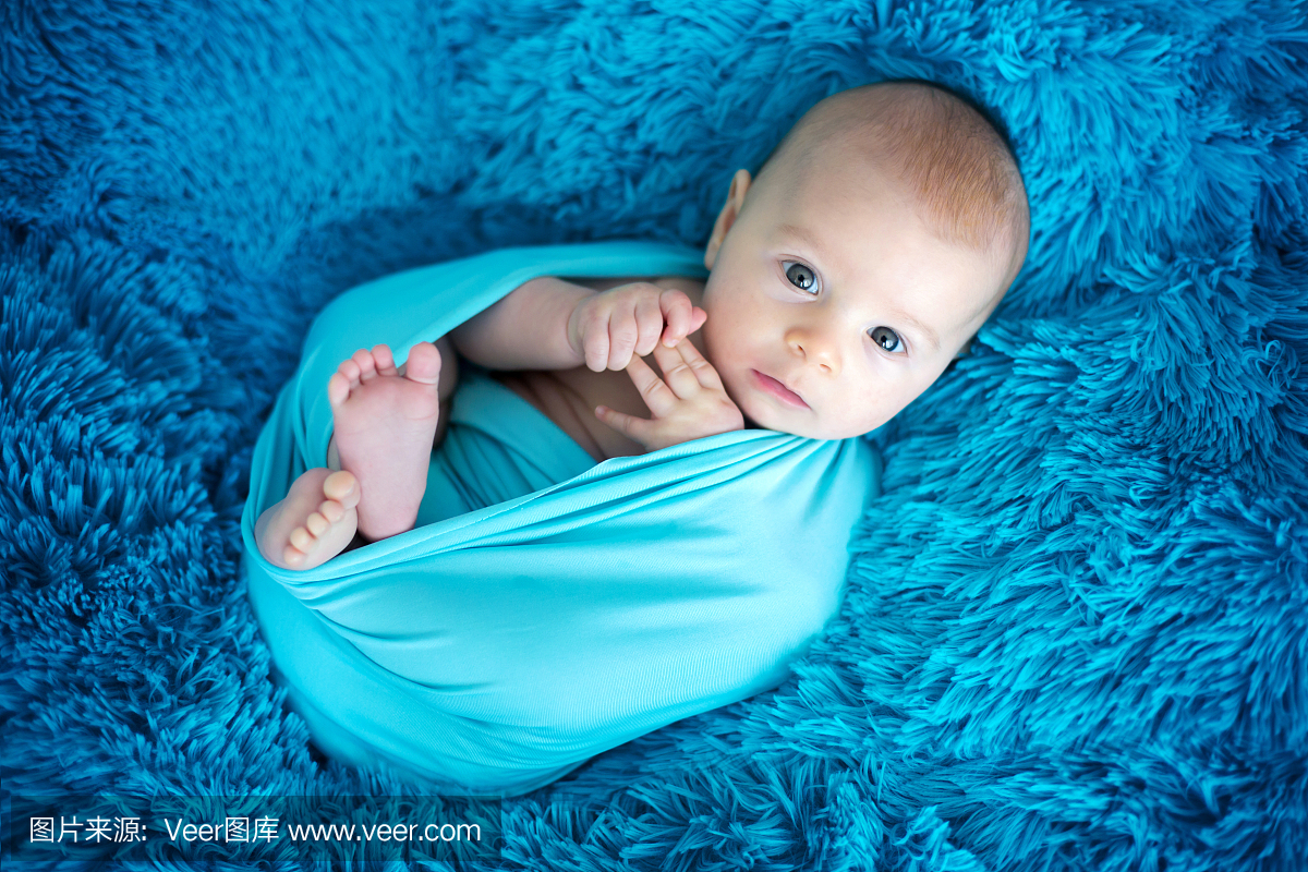 可爱的三个月大男婴在蓝色的包裹,躺在蓝色的