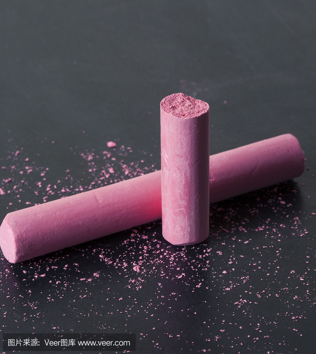 粉红色破碎的粉笔在粉笔粉笔的黑板上