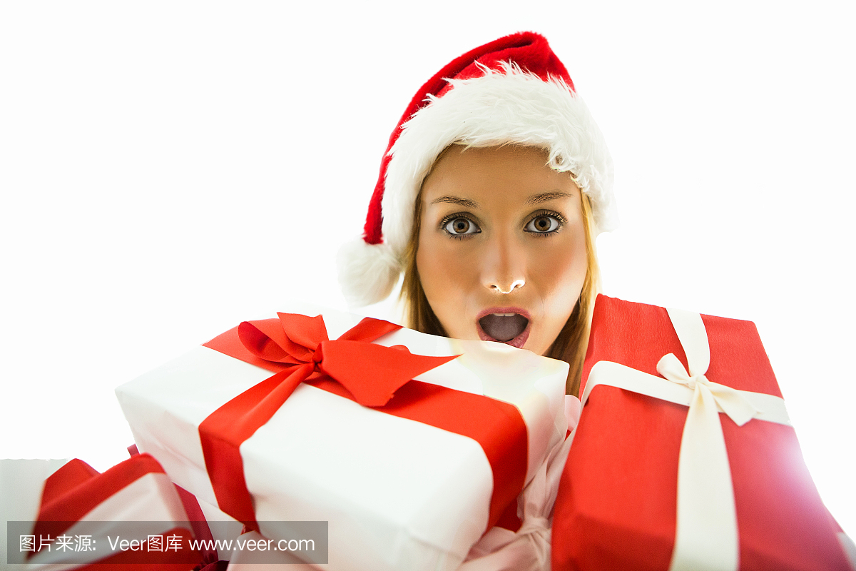 戴着圣诞帽子拿着红色和白色礼物的惊奇的女人