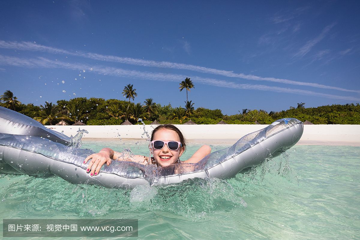 肖像微笑女孩玩充气筏在阳光明媚的热带海洋