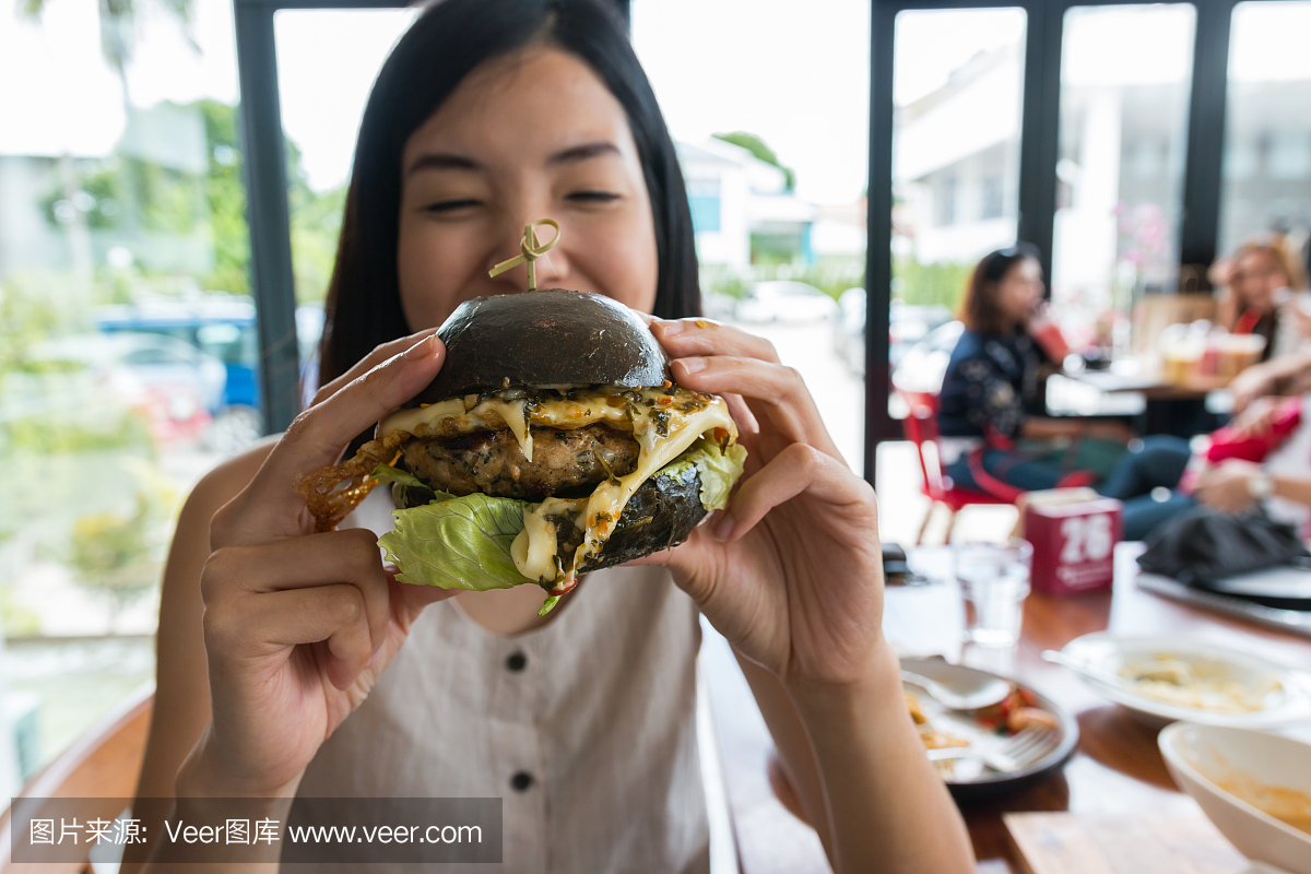 女人喜欢吃一个黑啤酒汉堡包