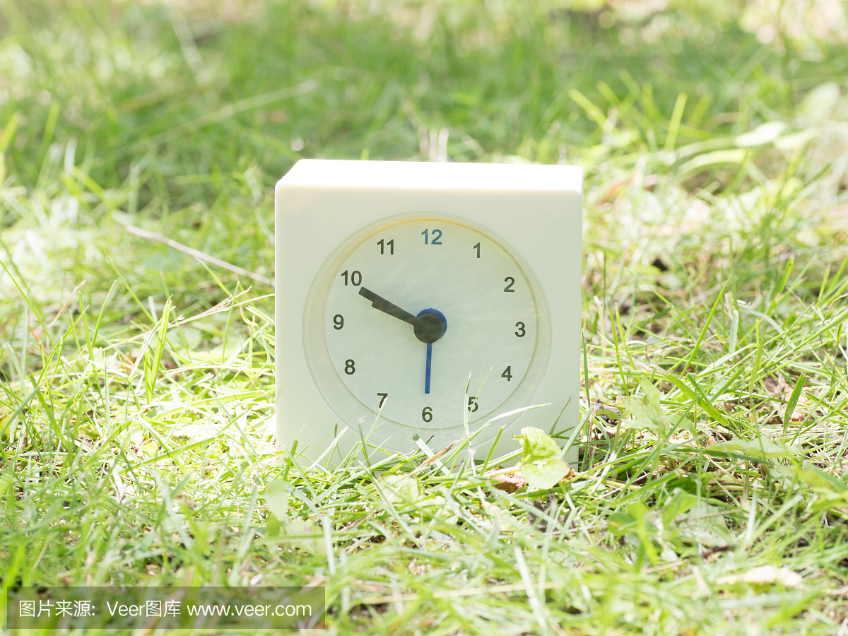 白色简单的时钟在草坪上,9点50分九点钟
