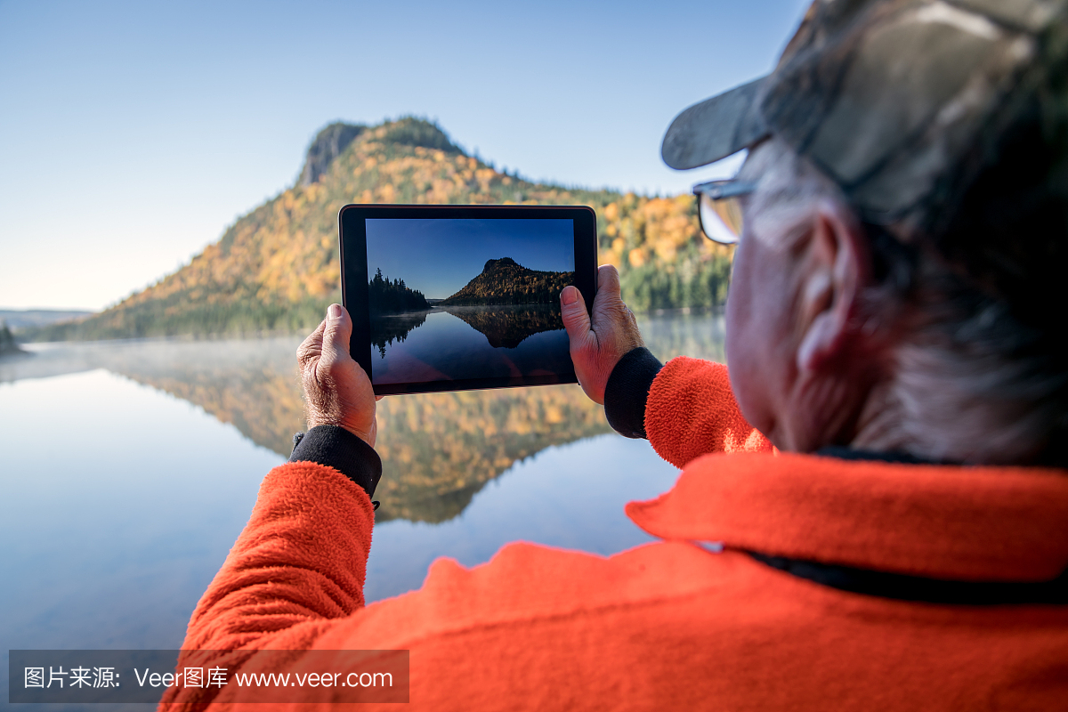 老人用数字平板电脑拍摄湖泊自然的图片