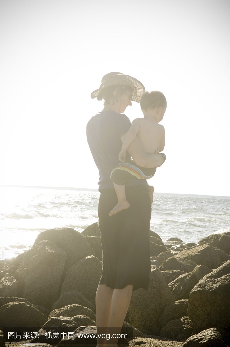 母亲抱着儿子站在大西洋附近的岩石上
