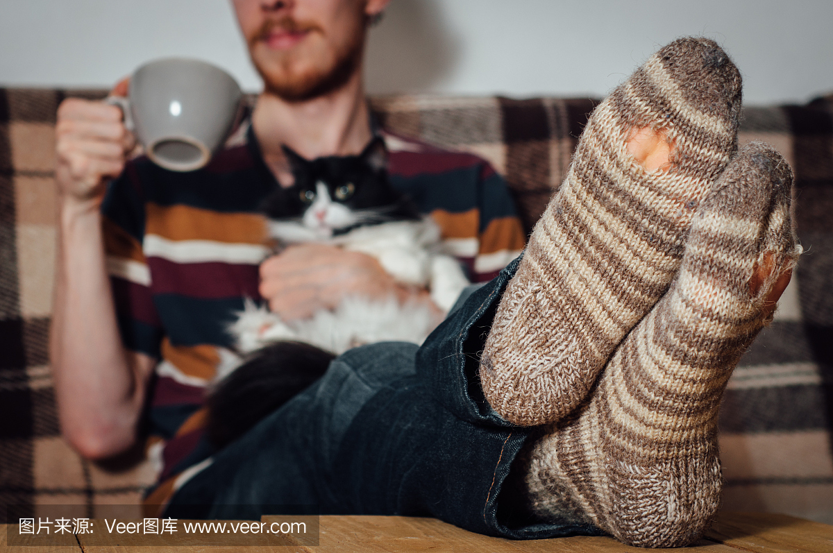 年轻的男子坐在教练与猫在多孔的袜子