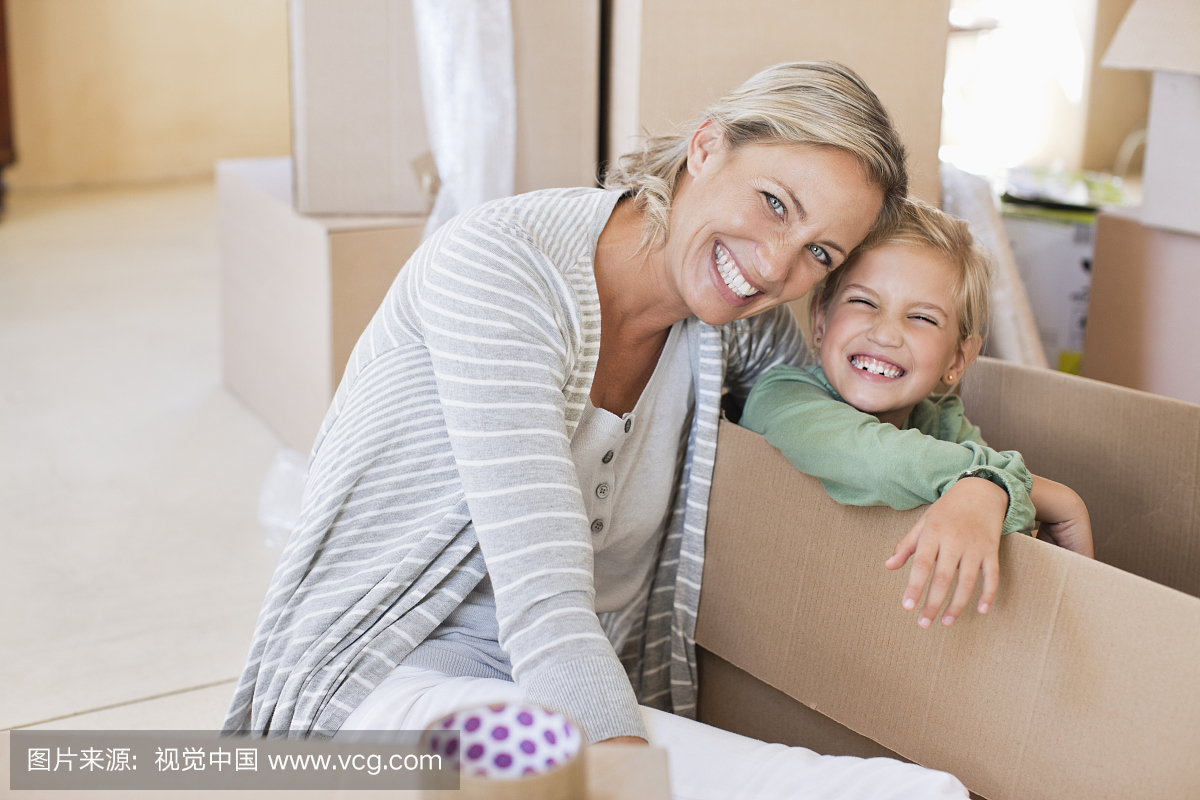 快乐成熟的女人与她的女儿解开纸箱在新房子