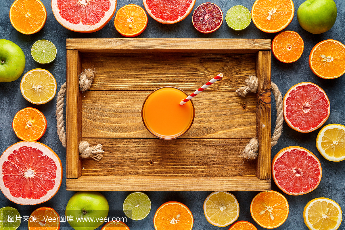冰沙或新鲜果汁在木托盘在柑橘类水果背景平躺