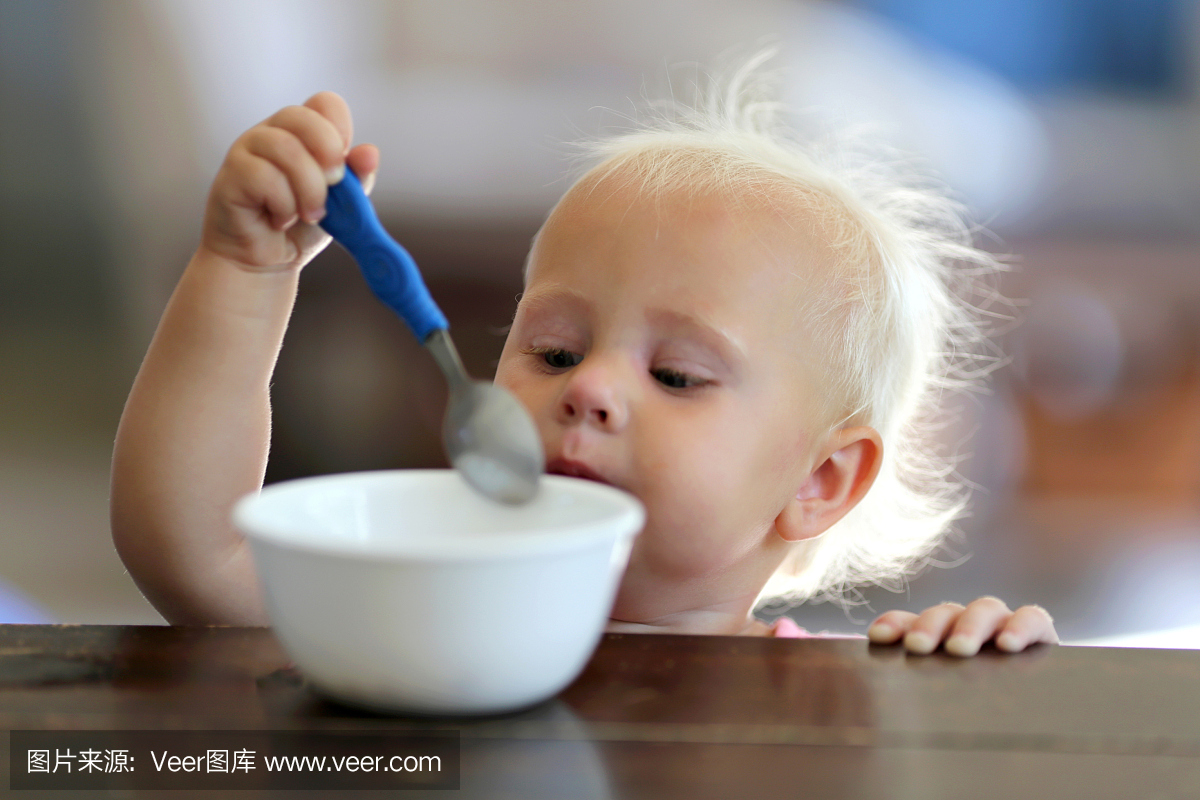 一岁的小女孩吃勺子的谷物
