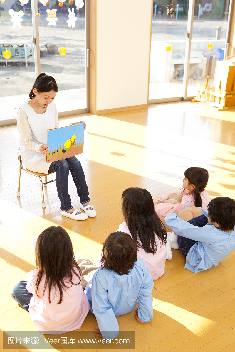 5名幼儿园小孩仔细听着后面的照片