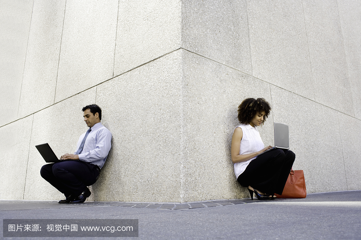 商人和女人靠墙使用笔记本电脑,表面水平