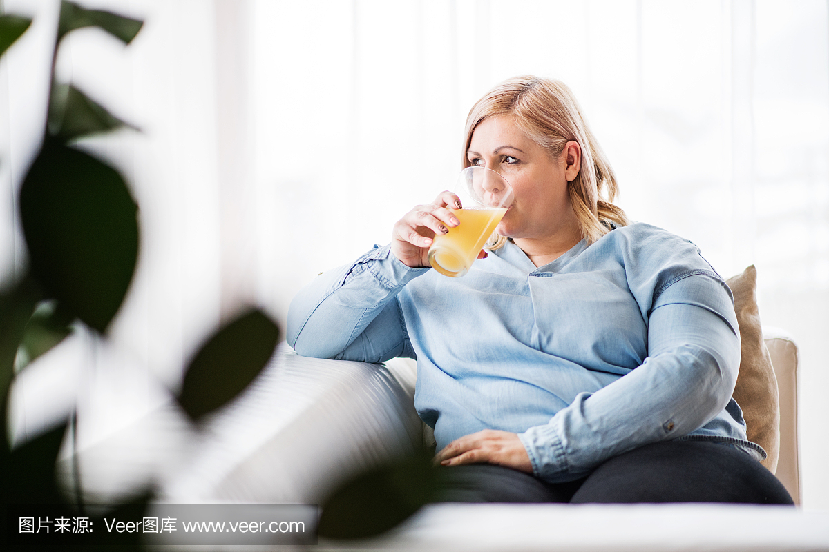 一个有吸引力的胖女人在家喝果汁。