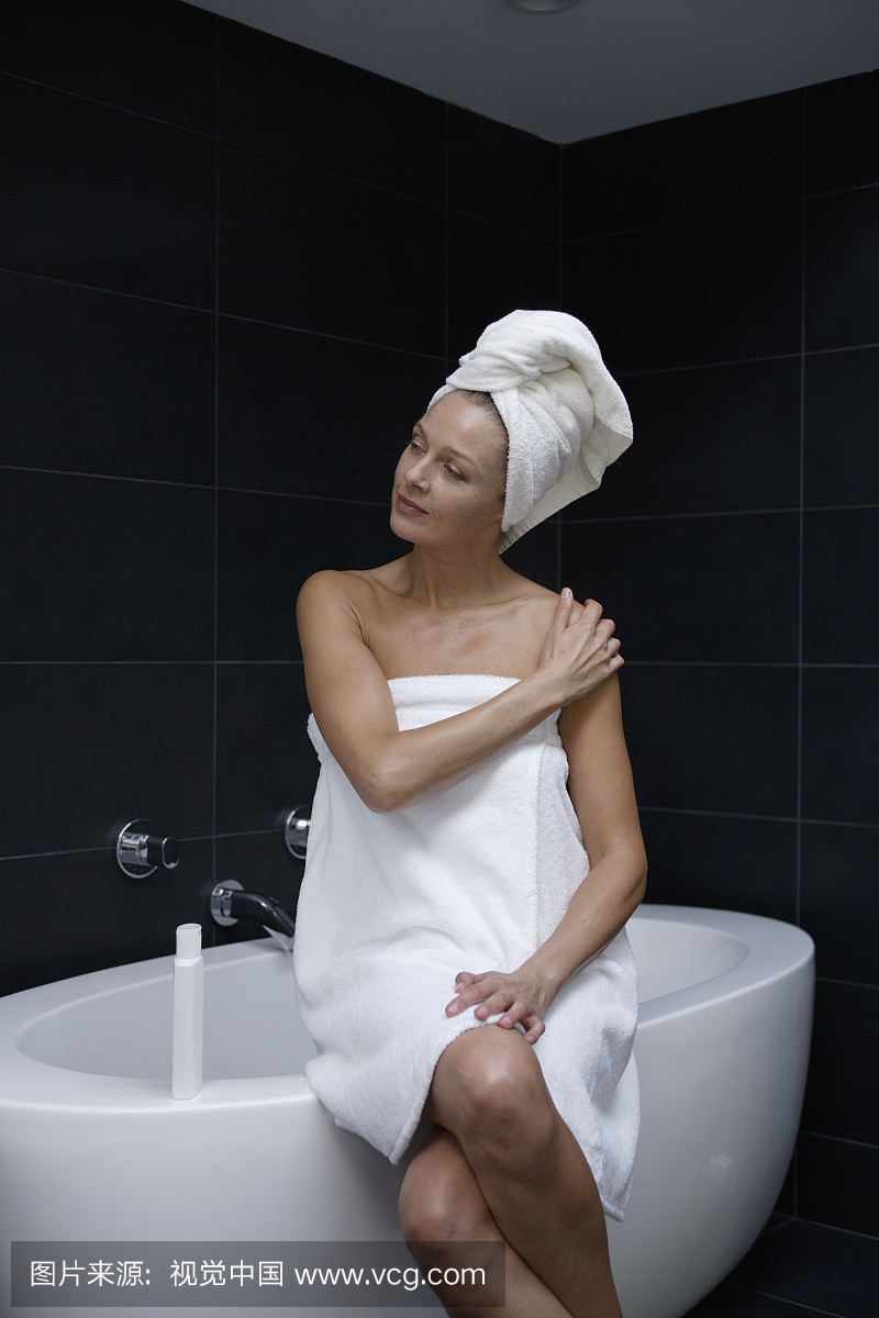 成熟的女人坐在浴巾里裹着毛巾
