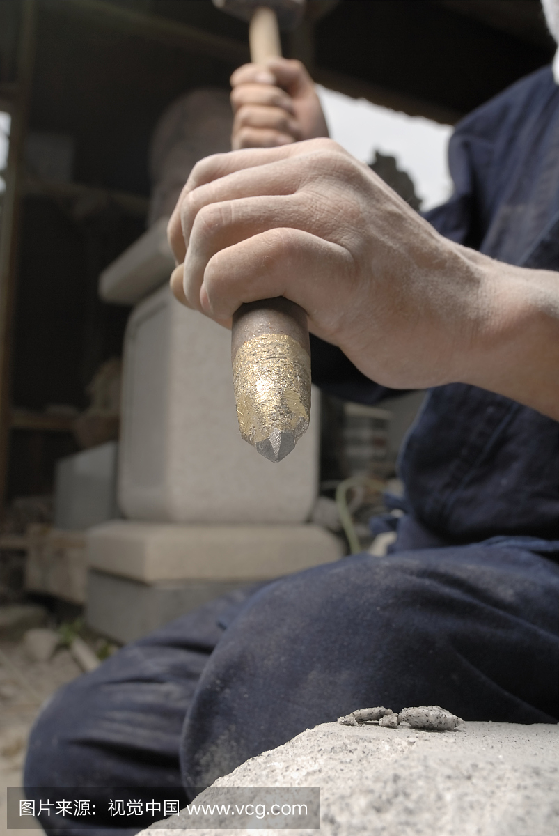 雕刻家雕刻石头与锤子的中段视图
