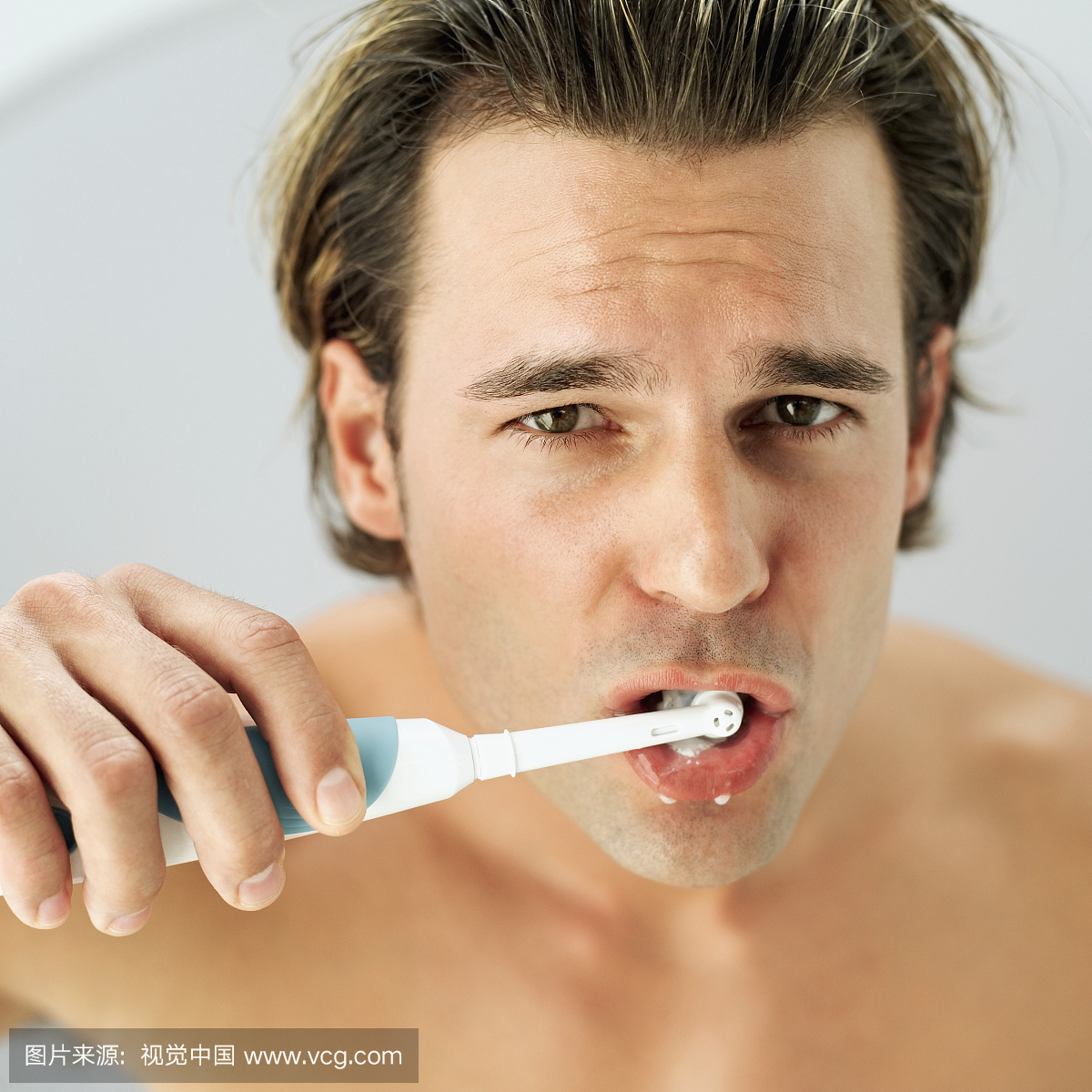 用电动牙刷刷牙的年轻人的肖像