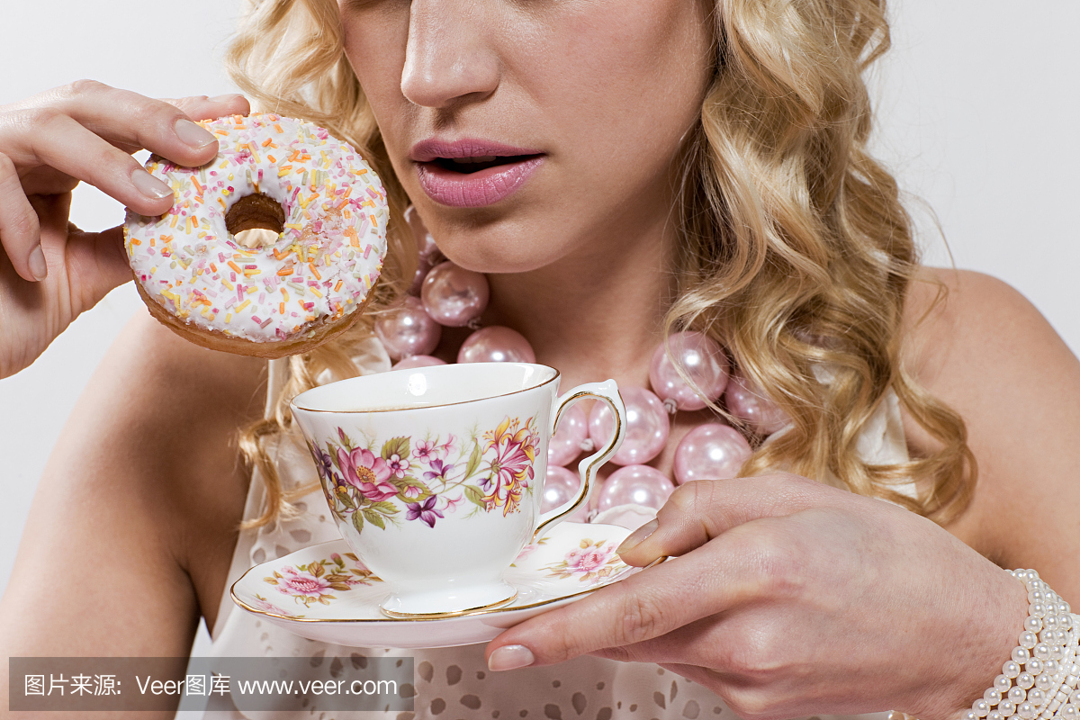 年轻女子与甜甜圈和杯茶