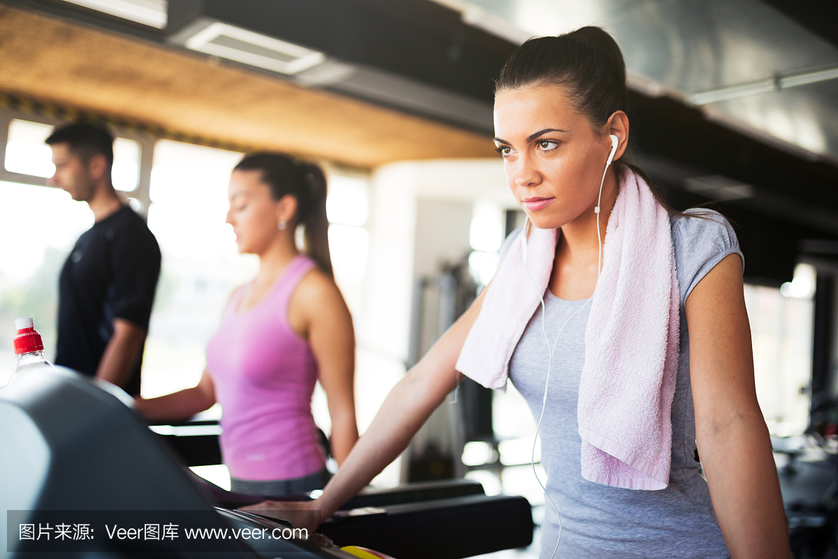 年轻女子在跑步机上锻炼时听音乐。