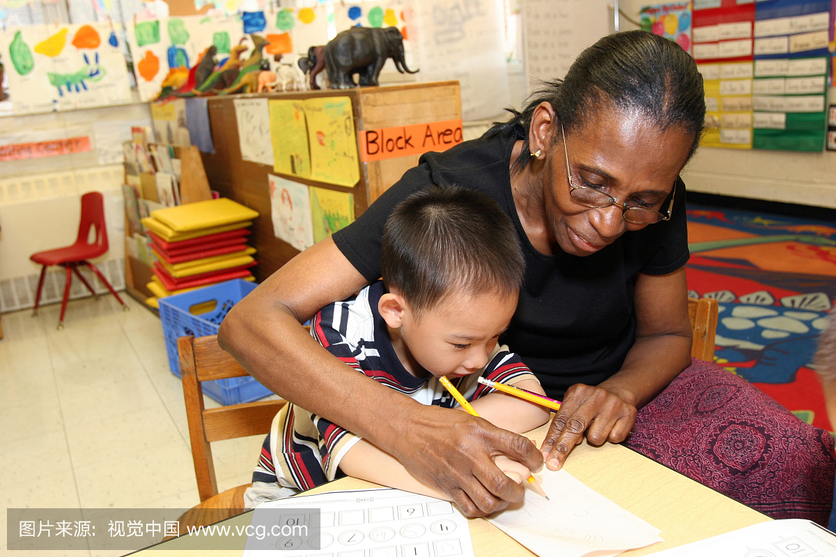 老师在纽约市日托中心帮助学生写作技巧。