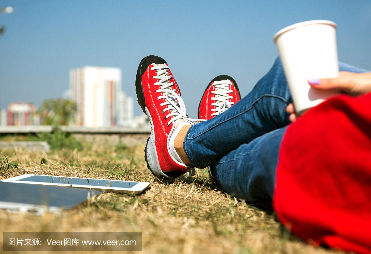 牛仔裤女孩和红色夹克鞋放松在公园