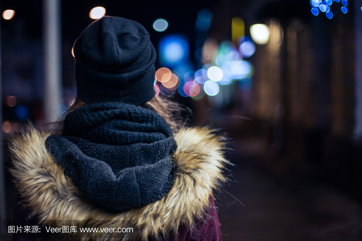 孤独的女孩在晚上在城市街道上走
