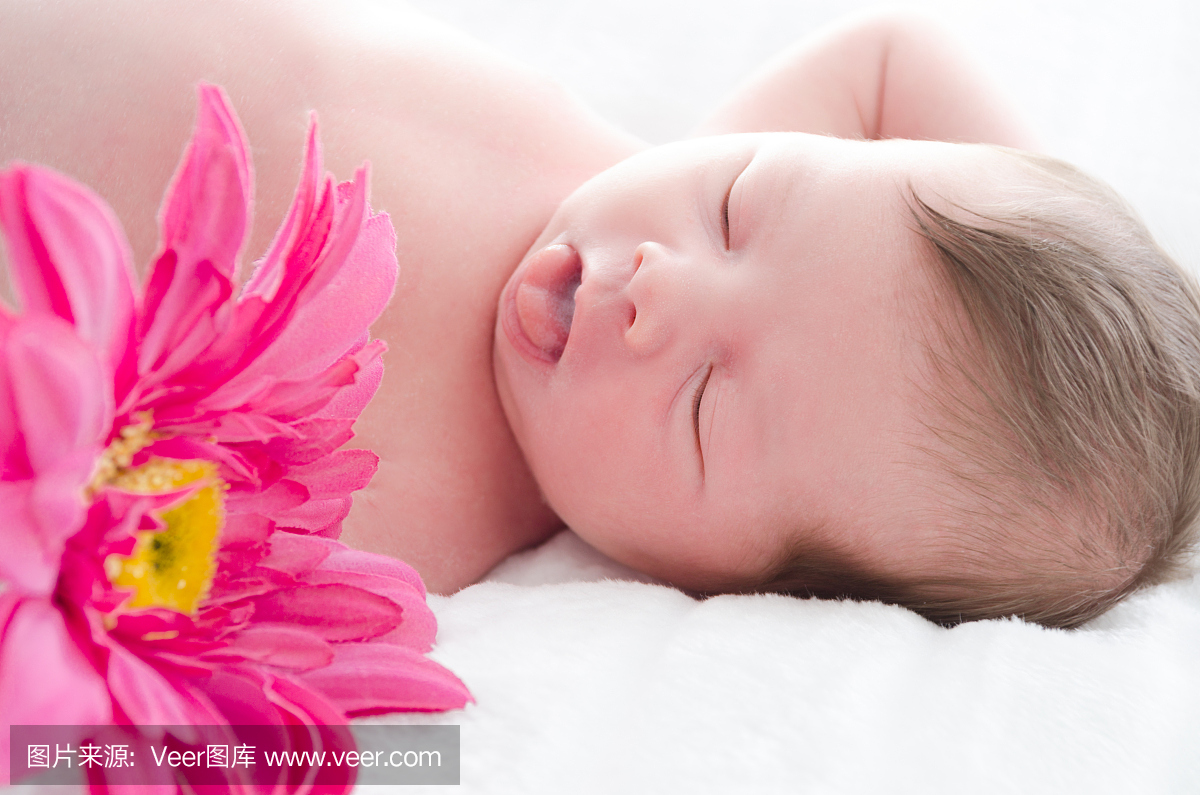 睡着的新生儿用舌头伸出来和花。