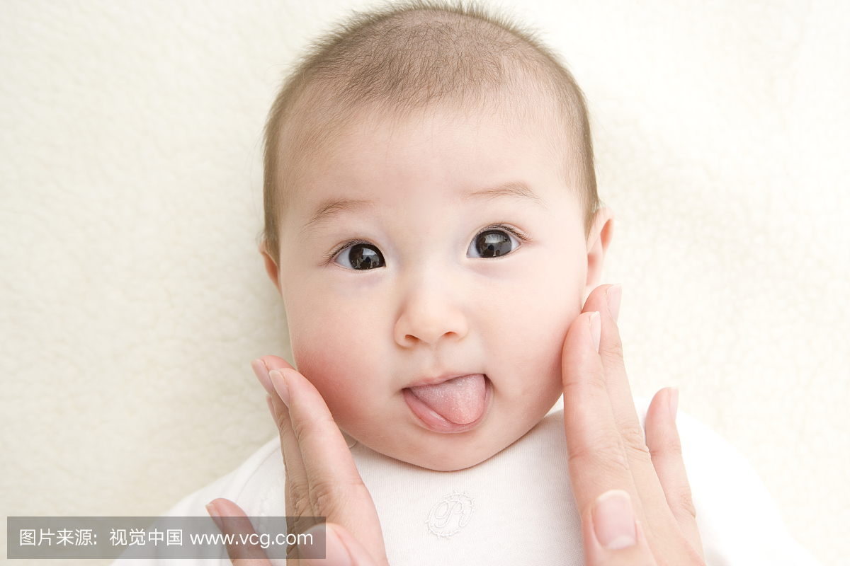 女人触摸女婴(3-6个月)的脸,宝宝伸出舌头