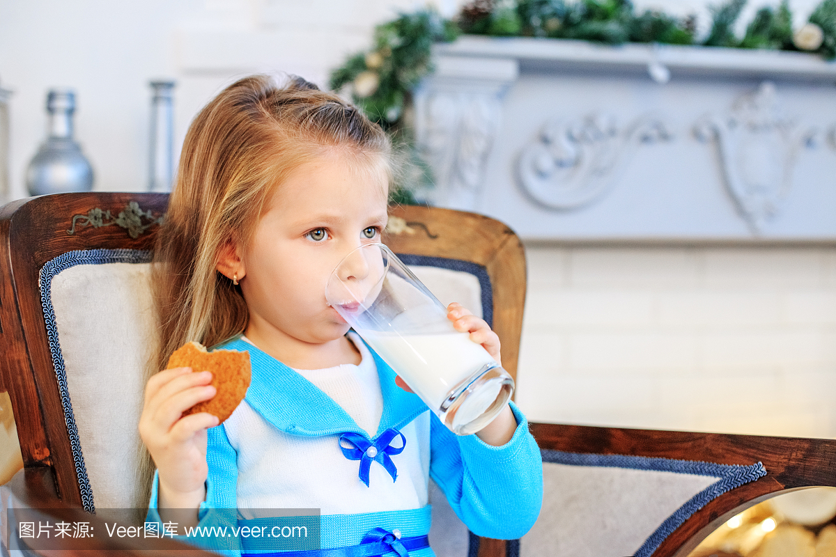 一个漂亮的婴儿喝牛奶并吃饼干。早餐。概念新