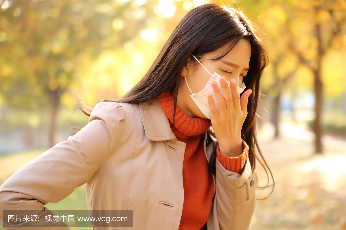 女人戴着医用口罩和咳嗽在公园里