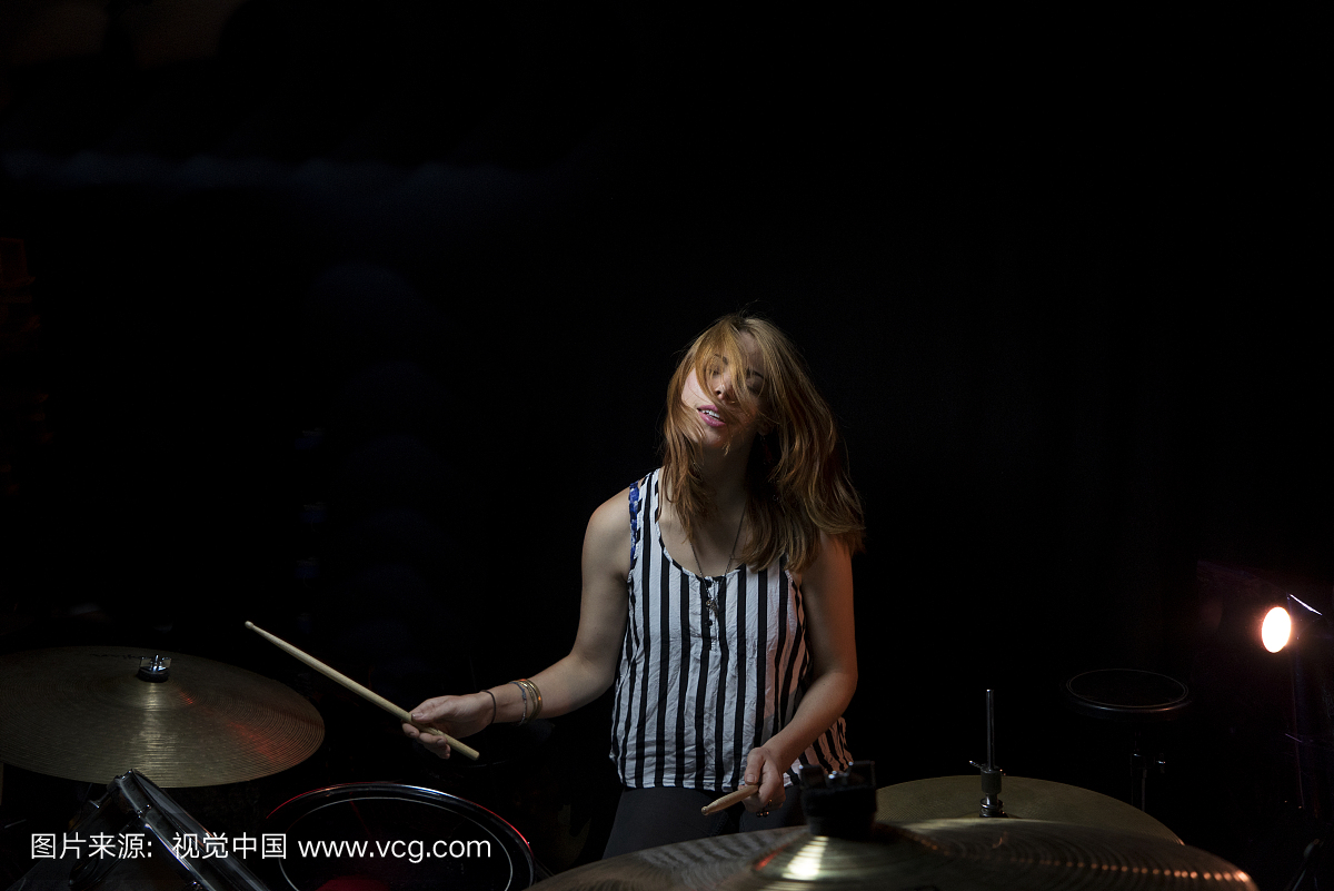 在舞台上演奏鼓的美丽的女人