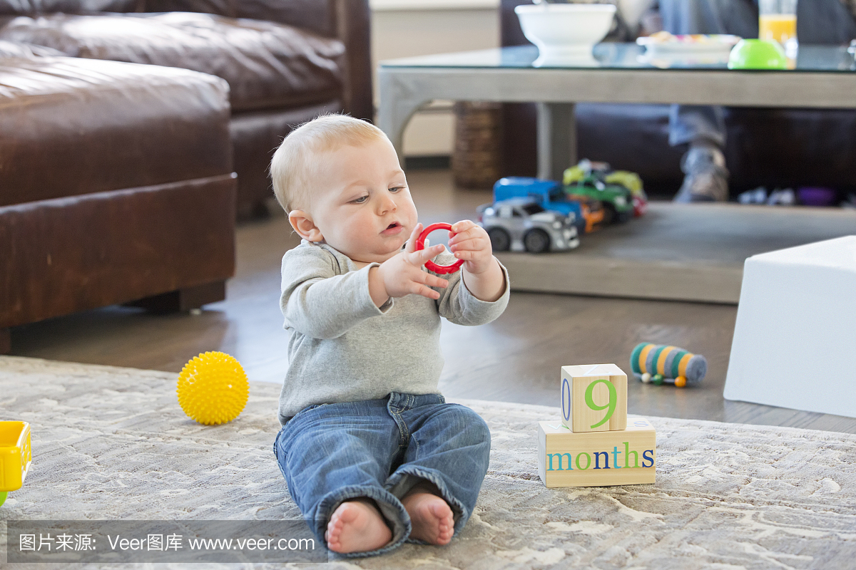 九个月大的男孩在地板上玩玩具