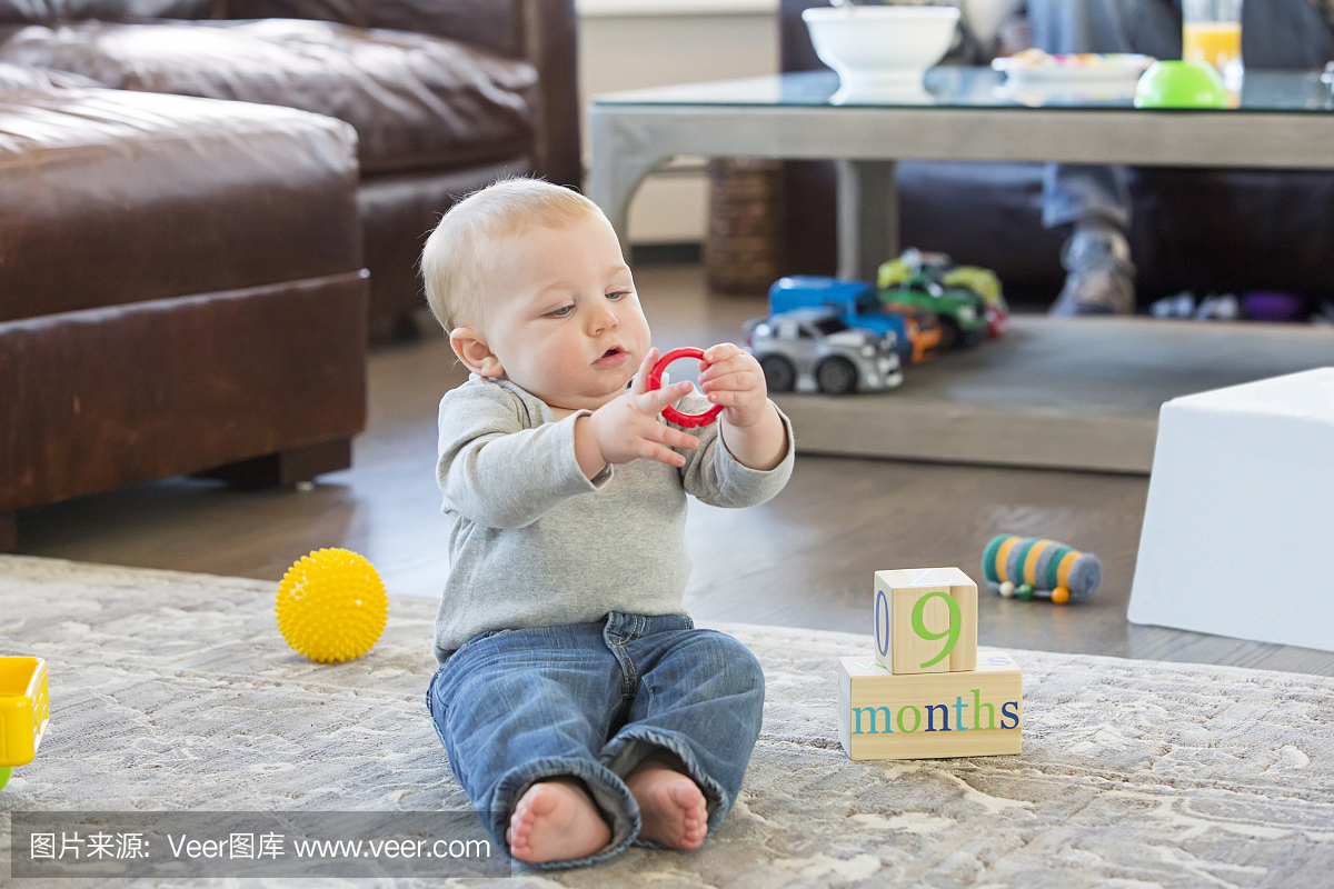 九个月大的男孩在地板上玩玩具