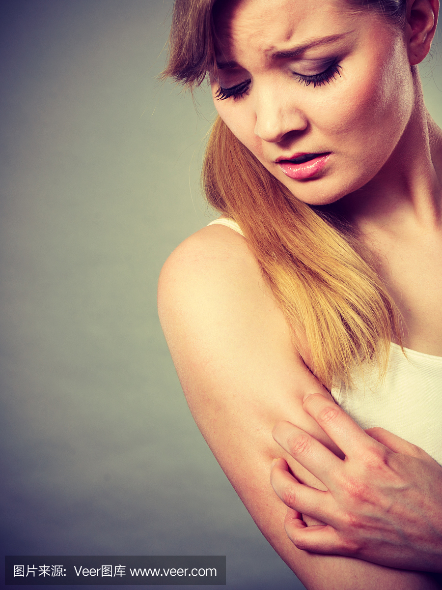女人抓挠她的痒手臂与过敏性皮疹