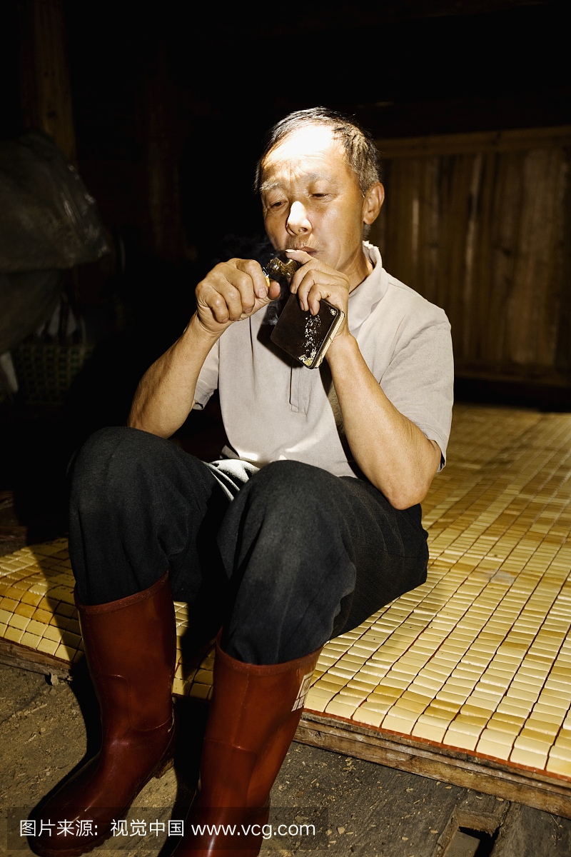 老人照亮雪茄,中国广西省金坑梯田