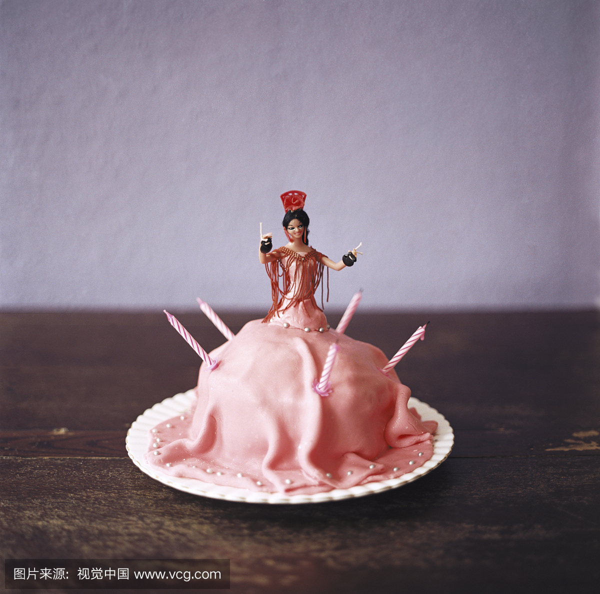 粉红色的蛋糕形状像弗拉门戈舞蹈员在桌子上,