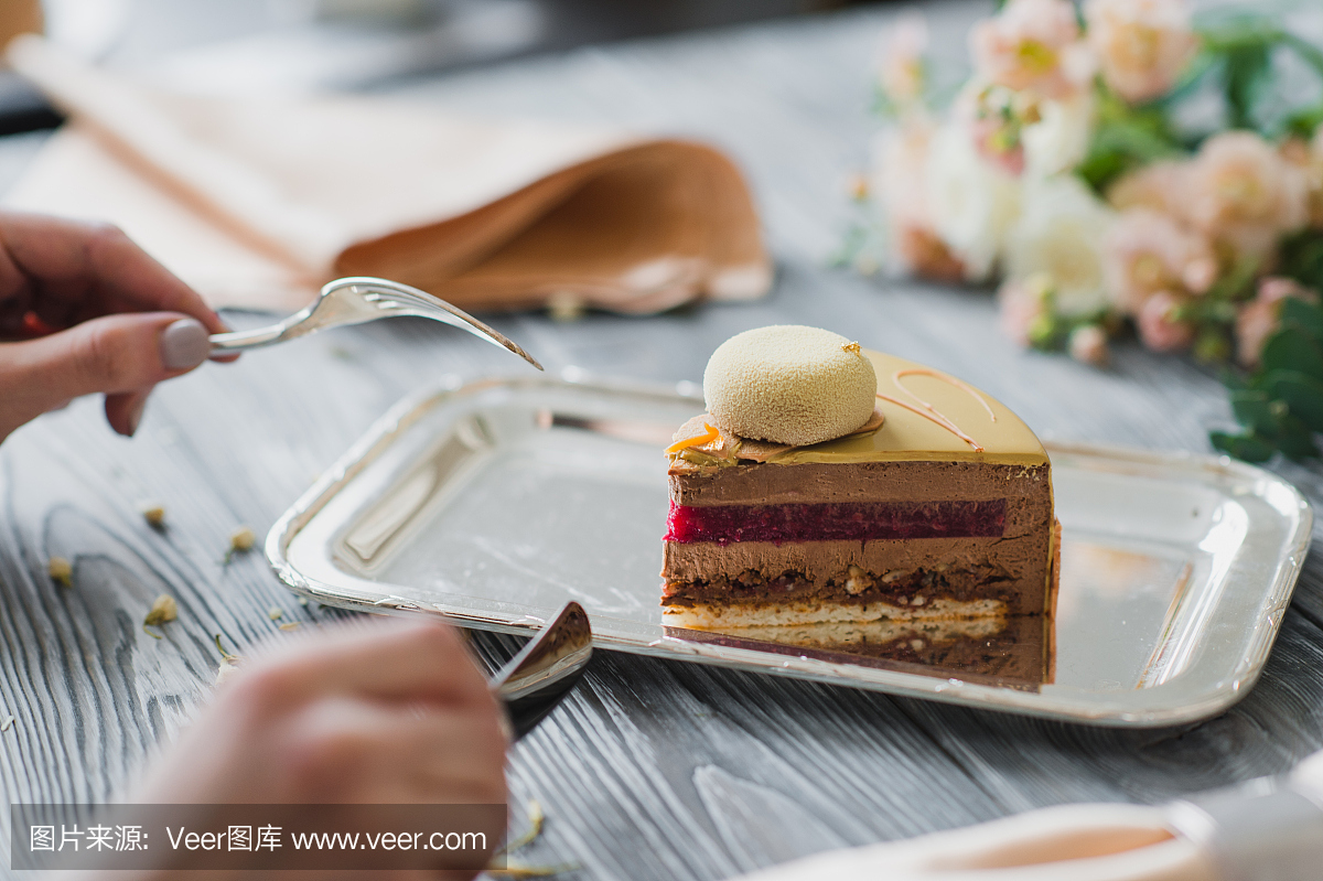 手去吃点心,黄色慕斯蛋糕与杏仁胭脂红色,覆盆