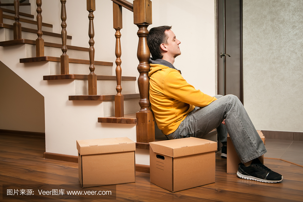 搬家年轻人与纸板箱在楼梯上。