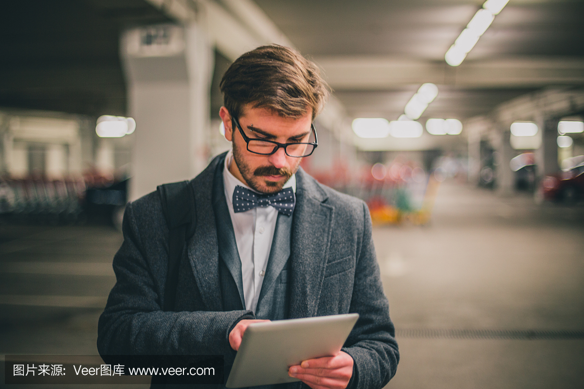 时尚的年轻商人在停车场使用数字平板电脑